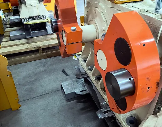 Equipos industriales con brazos naranjos y carcasa crema en galpón de maestranza