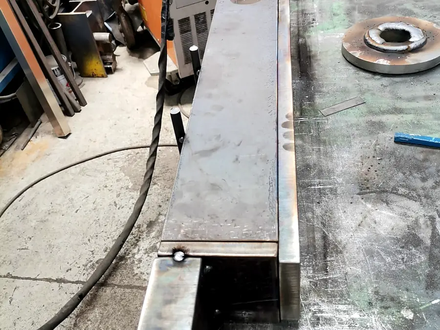 Cajón de plancha de acero soldado sobre la mesa de soldadura del taller