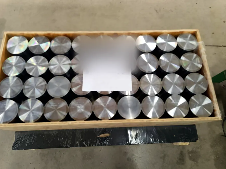 Cajón de madera con decenas de cilindros de acero torneados y marcados en filas