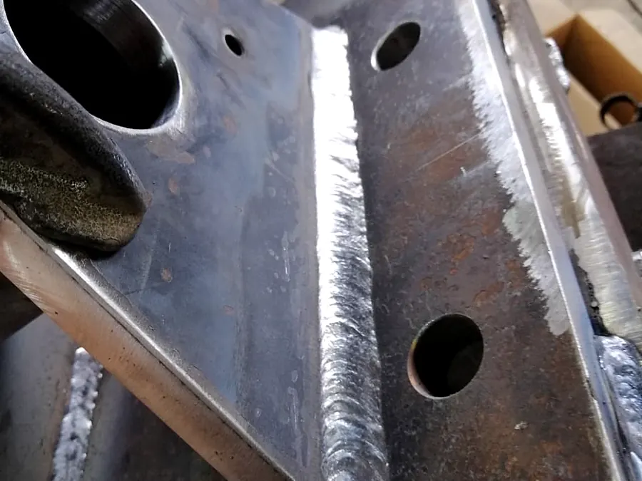 Primer plano de cordón de soldadura en soporte de acero con perforaciones