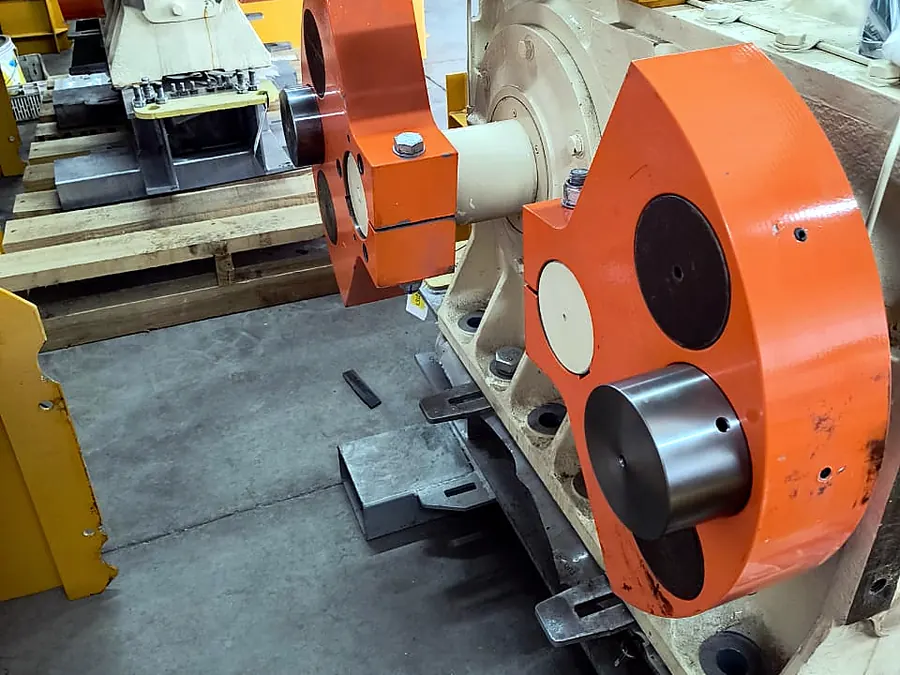 Equipos industriales con brazos naranjos y carcasa crema en galpón de maestranza