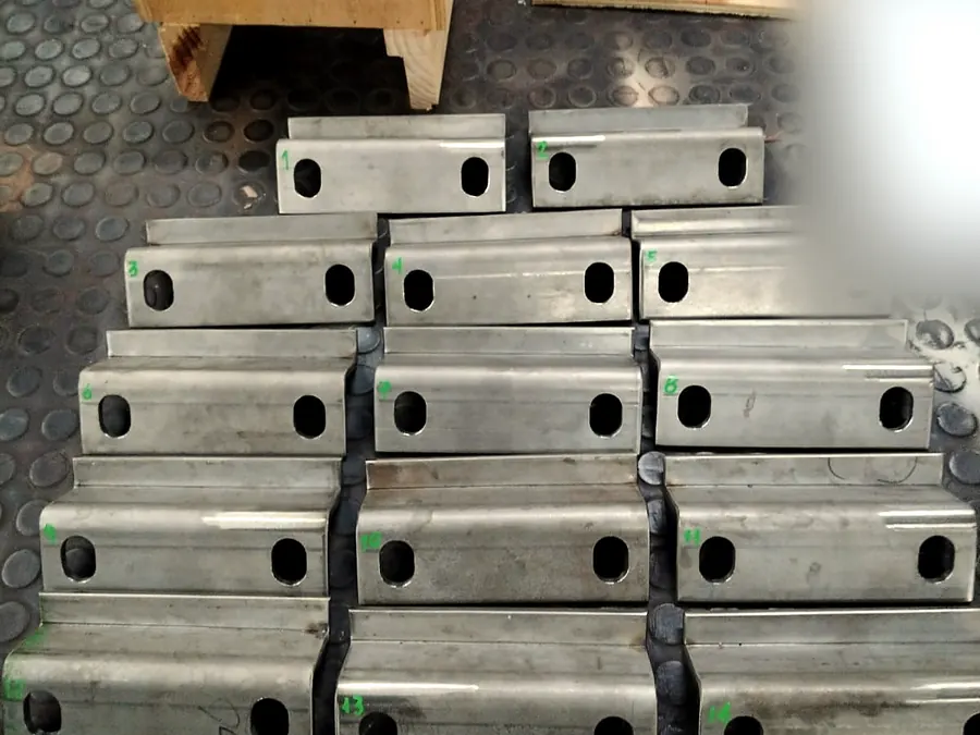 Catorce piezas de plancha plegada con perforaciones oblongas, numeradas una por una