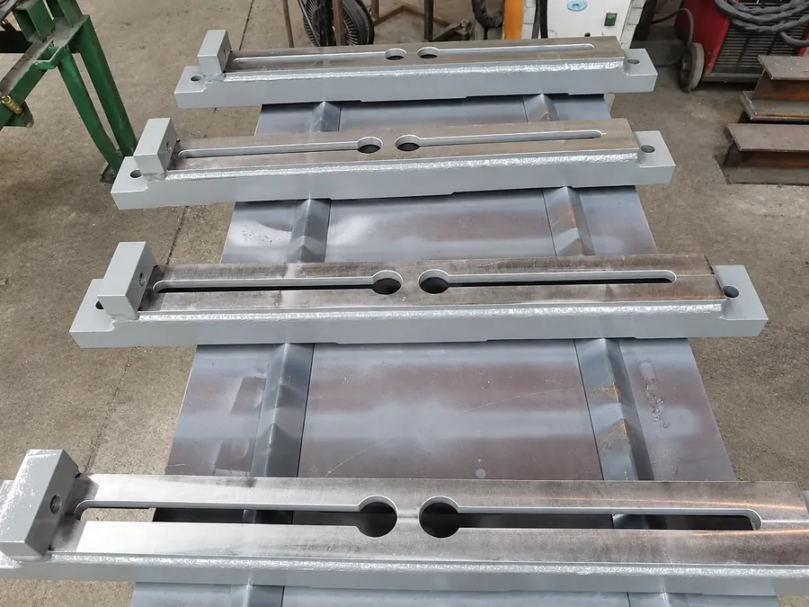 Cuatro soportes de acero con ranuras cortadas y soldadura pintados de gris