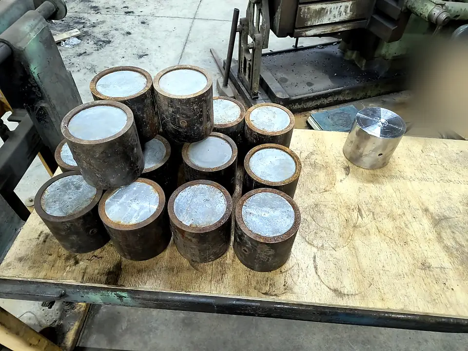 Tochos de acero oxidados agrupados sobre una mesa y una pieza igual ya torneada